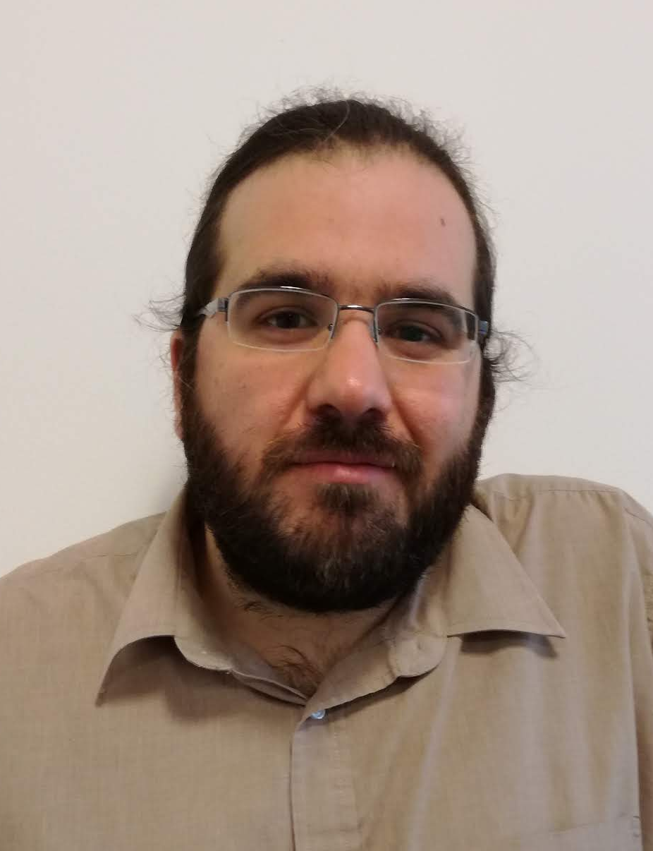 A headshot of smiling Bruno Bodin who has brown hair and a beard, wearing a brown shirt and half-rimmed glasses.