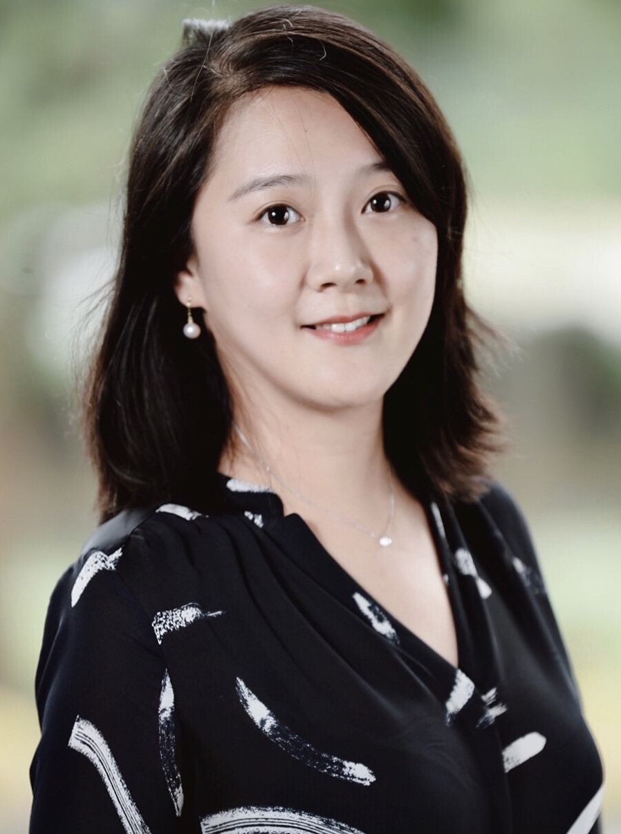 A headshot of smiling Pei Gao who has short black hair of shoulder length, wearing a necklace with a pearl pendant, pearl earrings, and a black blouse.