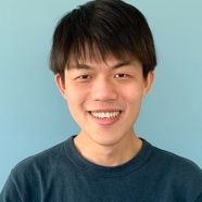 A headshot of smiling Lee Yi-Chieh who has short black hair and a fringe. He is wearing a dark blue t-shirt.