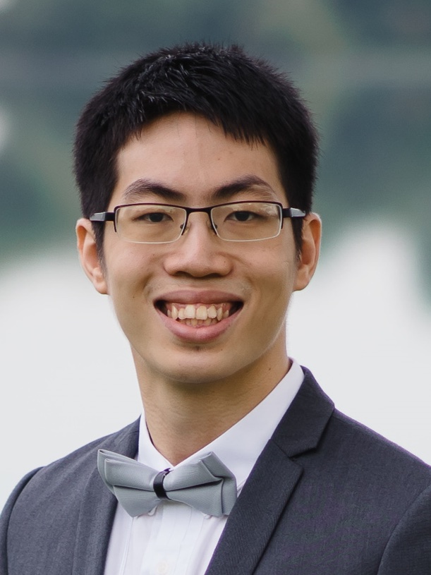 A headshot of smiling Bertrand Sim Sheng Long who has short black hair, wearing black-rimmed glasses, a light-grey bow tie, and a white collared shirt under a grey suit jacket.