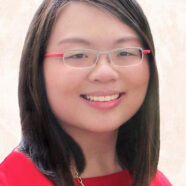 A headshot of smiling Sarah Shi Hui Wong who has short black-brown hair of shoulder length. She is wearing glasses with a grey and red frame and a red blouse and a gold necklace.